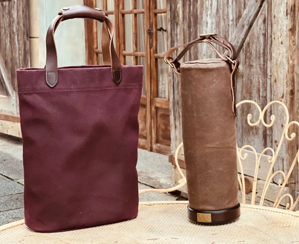 An image of a brown colored, cylindrical Vinarmour wine carrier next to a Vinarmour wine travel bag.