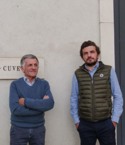 Two men stand in front of an exterior wall at Domaine Jean Michel Gaunoux-Fils.