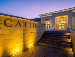 The exterior of the Joseph Cattin winery at dusk. Warm lighting illuminates the Cattin sign on the exterior wall.