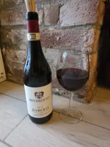 A bottle of wine next to a glass of red wine.