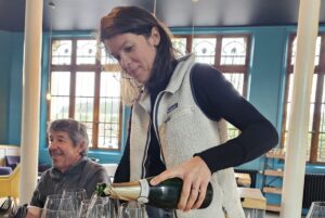 A woman pours several glasses of Champagne Hervé Dubois.