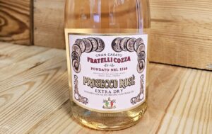 A bottle of Fratelli Cozza NV Prosecco Rosé Extra Dry resting against a wooden background.