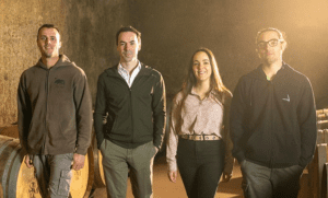 A group of 3rd generation winemarkers stands together in the Malvirà wine cellar.