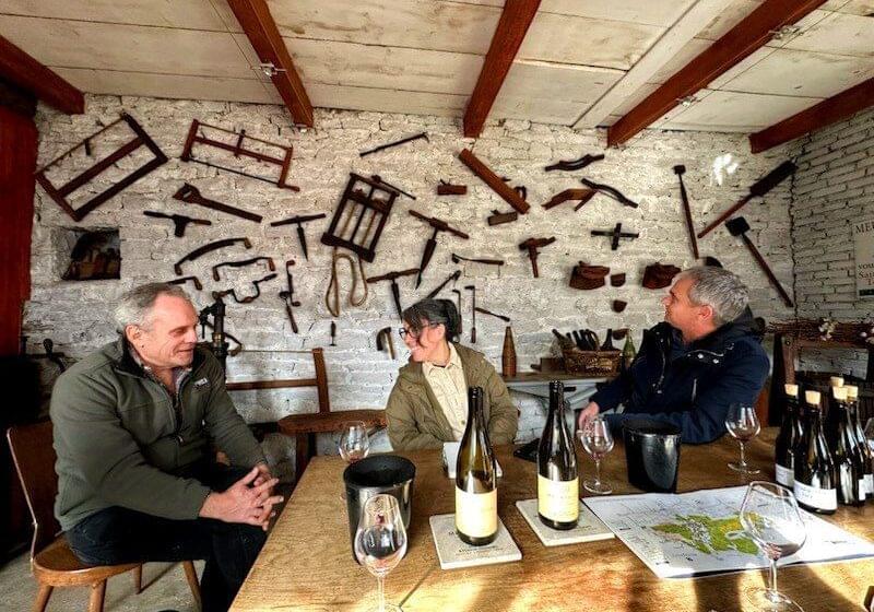Three people engaged in conversation at a rustic wine tasting room.