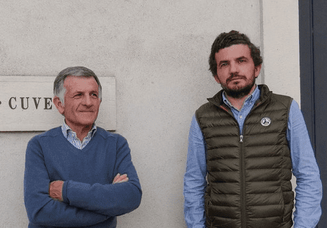 Two men stand in front of an exterior wall at Domaine Jean Michel Gaunoux-Fils.