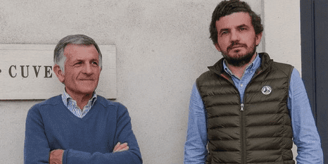 Two men stand in front of an exterior wall at Domaine Jean Michel Gaunoux-Fils.