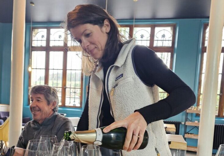 A woman pours several glasses of Champagne Hervé Dubois.