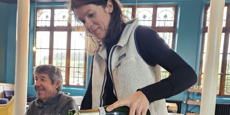 A woman pours several glasses of Champagne Hervé Dubois.