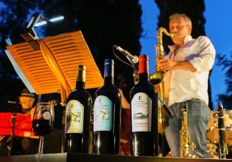 A man plays saxophone in the background while a number of Fattoria Uccelliera bottles sit in the foreground.