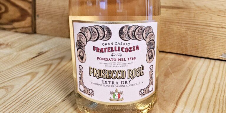 A bottle of Fratelli Cozza NV Prosecco Rosé Extra Dry resting against a wooden background.