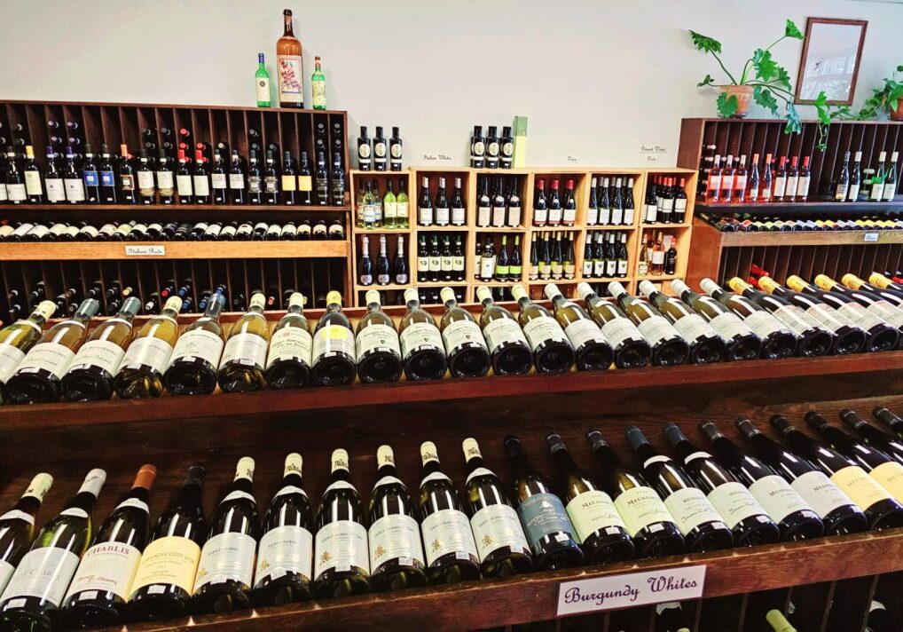 Interior of University Wines with multiple shelves stocked with assorted wine bottles.